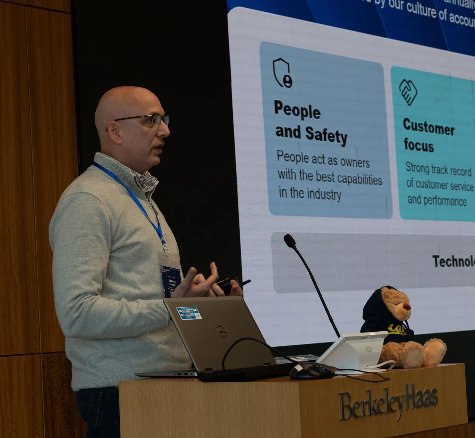 Joshua Guest speaking at the lectern in front of a slide listing people and safety, customer focus, and technology as the company's values